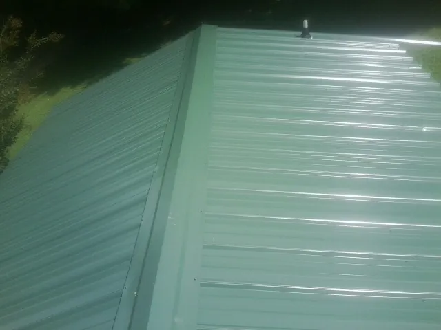New green metal panels meeting at the ridge of a roof — Flat Roof Repair work by our crew in Pomona