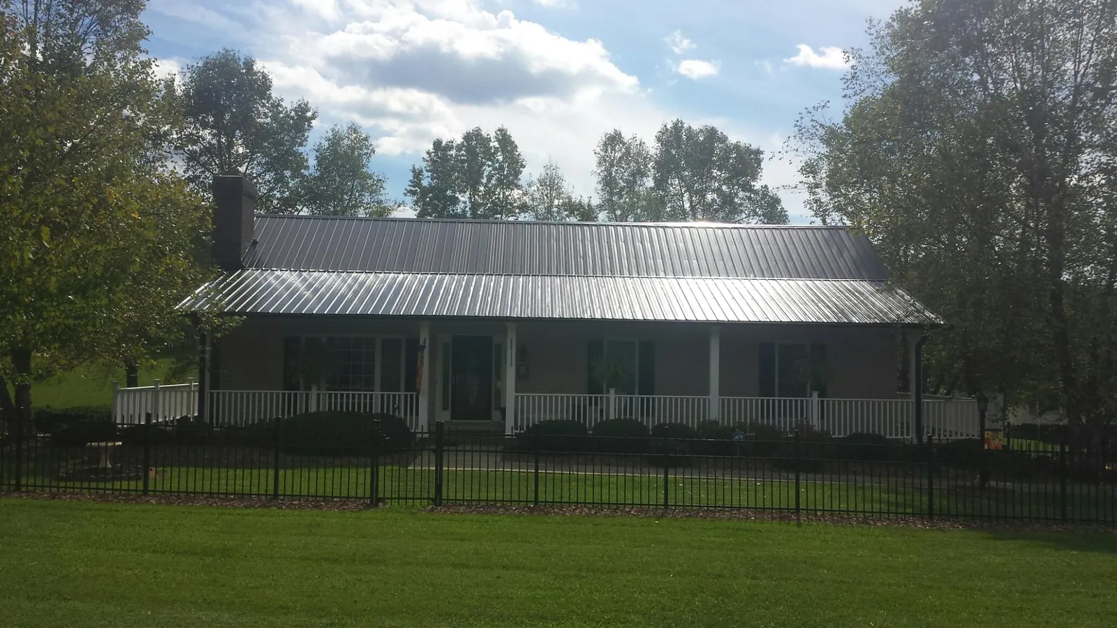 Gray metal roof on a brick ranch with a full width front porch — Gutter Guard Installation work by our crew in Pomona