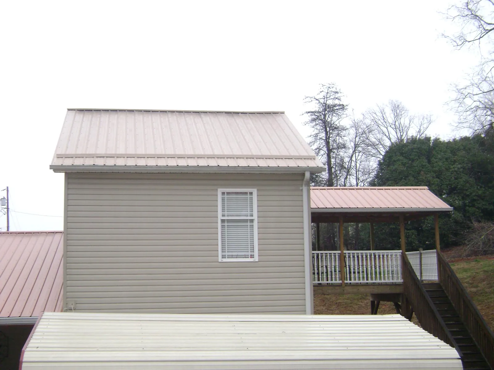 Tan metal roofs on a two story addition and attached porch, from a Roof Replacement job in Pomona